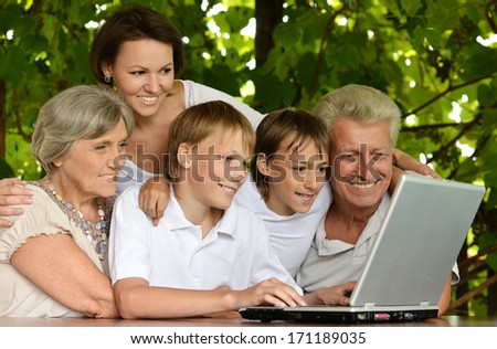 Portrait of happy family with the computer at outside terrace