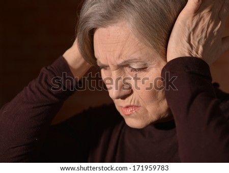 Portrait of thoughtful sad elderly woman. Hands near head