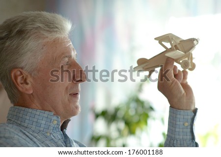 Senior man with wooden plane at home