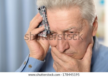 Sick old man standing on blue background