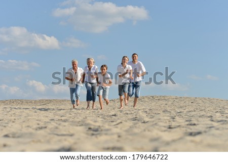 big happy family  running barefoot in the sand in the summer