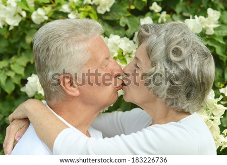 Happy elder couple kissing on white flowers background