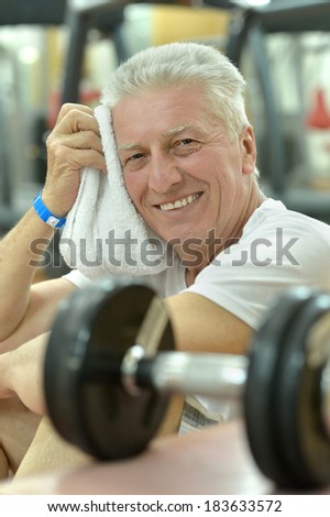 Elderly man in a gym. exercising with dumbbells