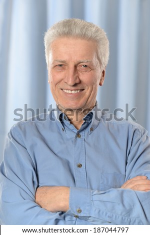 Cute older thoughtful man poses on blue background