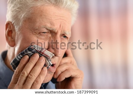Sick old man with tooth pain standing on colored background