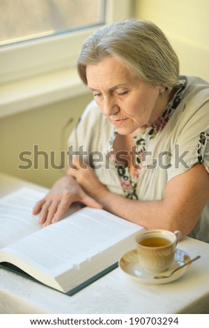 Nice older woman sitting in the room with book