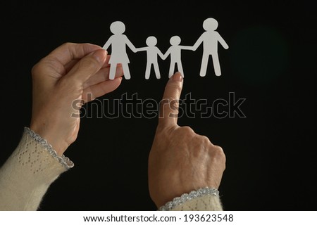 Paper  family in hands  on dark background