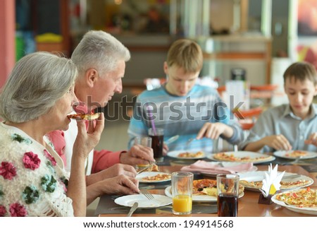 Big happy family eating pizza in cafe