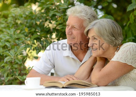 Nice elderly couple sitting at table during summer