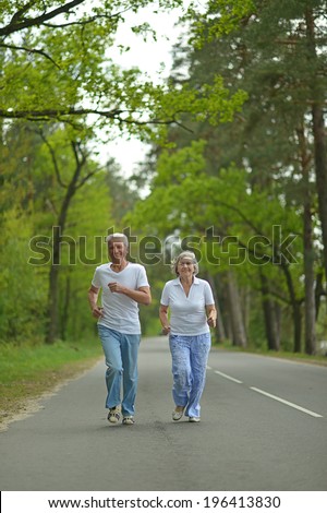 active senior couple run in summer forest