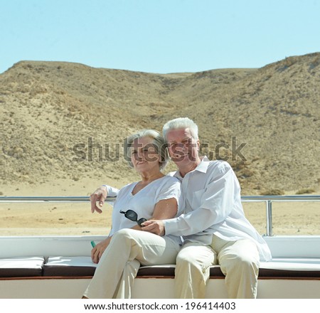 Amusing elderly couple have a ride in a boat on sea