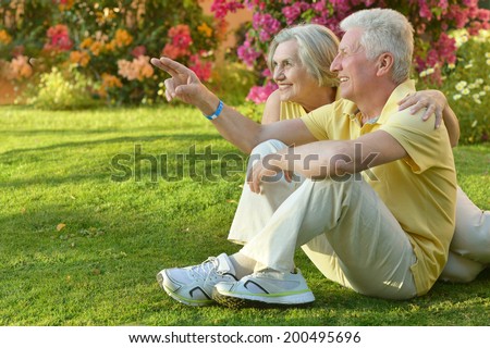 Happy elder couple resting on pink flowers background