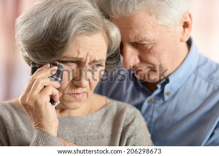 Close-up portrait of a sad elder couple on color background