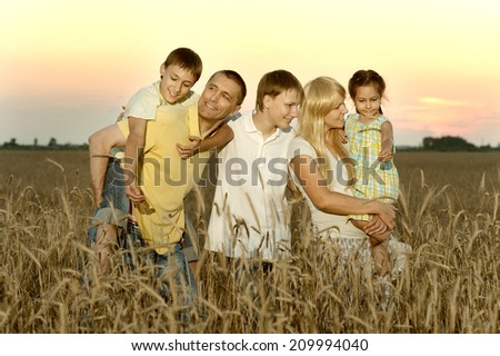 Friendly family walking in wheat field in evening