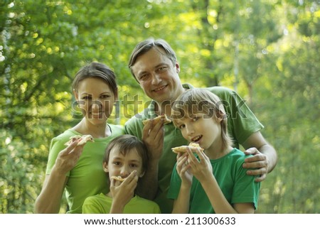 Happy smiling family eating pizza in the park