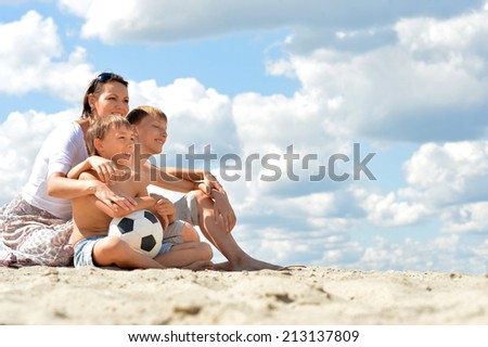 Happy family with soccer ball on beach in summer day