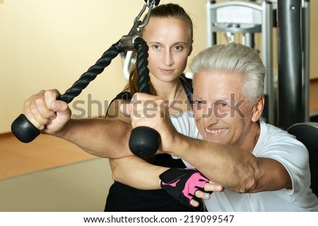 Elderly man exercising in gym with trainer