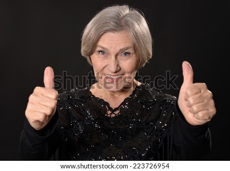 Happy smiling elder woman in elegant dress on black background