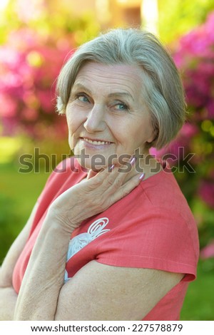 Portrait of an older woman in park with red flowers
