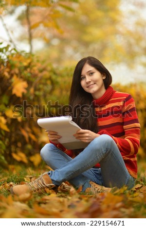 Beautiful young girl drawing in autumn park