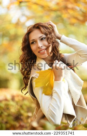 Beautiful young woman with leaves posing in autumn park