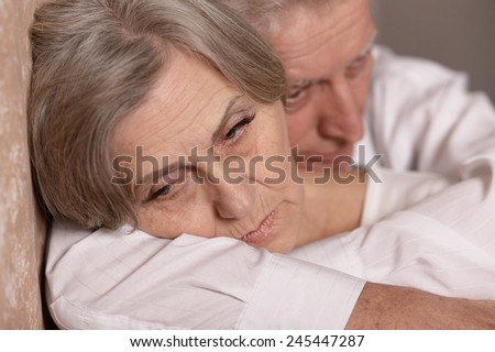 Close-up portrait of sad elder couple at home
