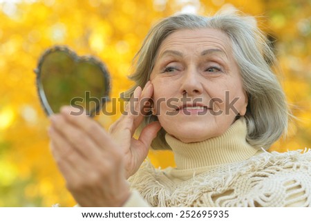Elderly woman with mirror in autumn