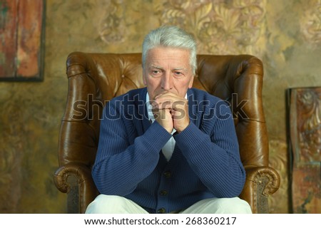 Elderly man sitting in armchair in room