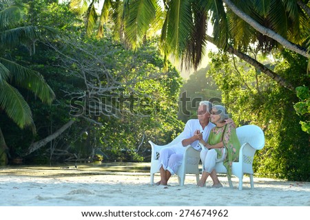 Beautiful  elderly couple sitting on a background of palm trees