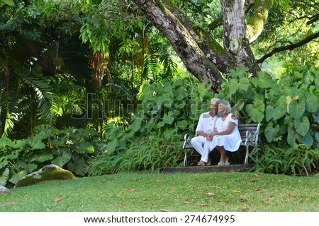 Happy elderly couple sitting on a bench outdoors