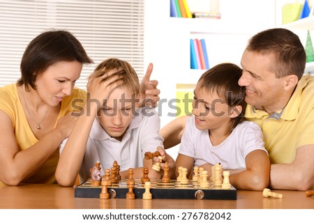 Happy family playing chess sitting at table