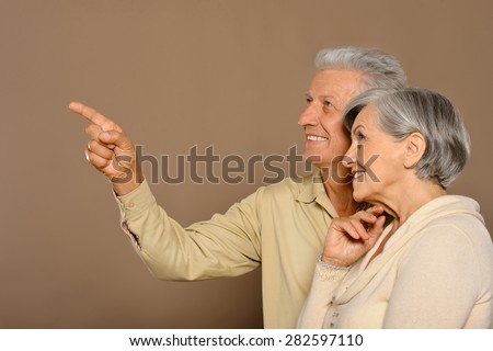 Amusing happy smiling old couple,man pointing by his hand