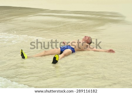 Portrait of a happy elderly man lying  on beach
