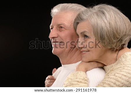 ortrait of older couple embracing on a black background