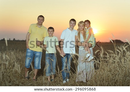Family having rest in field at sunset