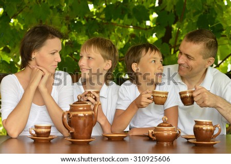Happy family drinking tea in summer garden