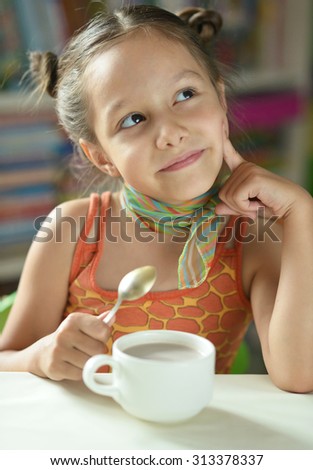 Cute little girl with  cup of cocoa  on the table
