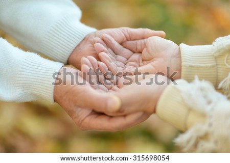 Elderly couple holding hands in field close-up