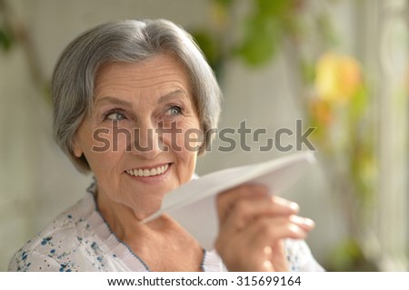 Portrait of beautiful senior woman with paper plane