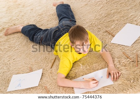young boy drawing on the carpet on white