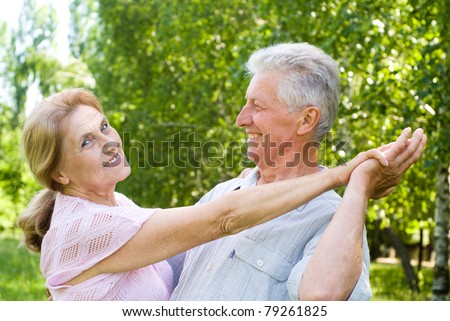 happy old couple dancing at the park