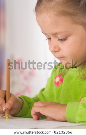 little girl at table drawing on a white