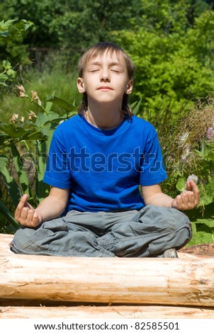 cute young boy meditates at the  nature