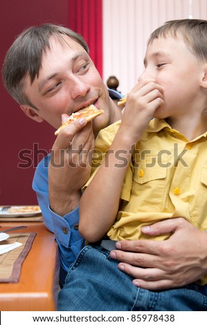 portrait of a cute dad and son eating pizza