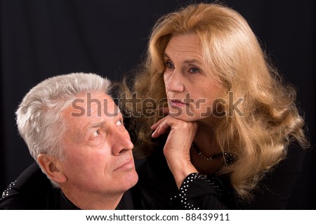 cute old man and woman posing on black