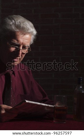 portrait of an old man with newspaper in dark