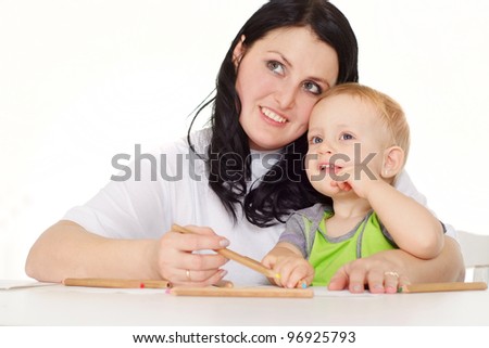 Pretty good loving mother and daughter sitting at a table with pencils