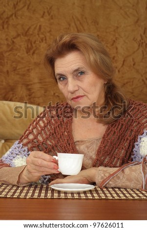 luck elderly woman sitting on a sofa on a brown background