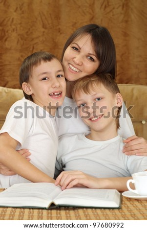 A beautiful Caucasian joy mother with two adorable brothers on a brown background