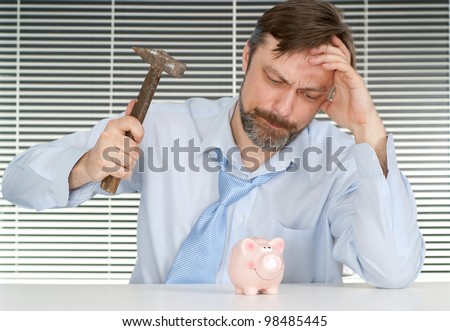 Business man sitting breaks piggy bank on a light background